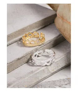 Close-up of wavy textured S925 silver rings in gold and silver on stone base