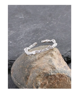Macro detail of S925 silver liquid lava ring showing irregular vine textures on a rock