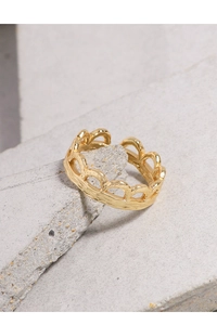 Close-up of gold crown hollow ring with scalloped edges on gray stone background