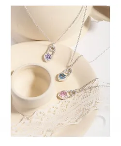 Detailed view of silver heart necklaces with purple blue and pink stones on a ceramic plate