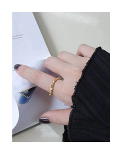Detailed view of an irregular textured gold ring on a finger with a magazine backdrop