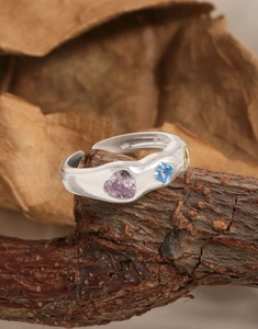 Macro detail of S925 sterling silver ring with colorful zircons on natural wood bark