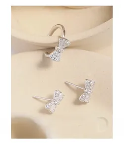 Detailed view of silver bow stud earrings and ear cuff with sparkling zircon inlay
