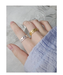 Close-up of wavy lace rings in gold and silver finish with textured surface on fingers