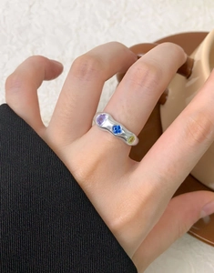 Detail of irregular silver wavy ring with inlaid purple, blue and yellow zircon gemstones