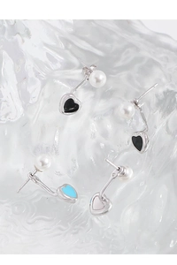 Détail de boucles d'oreilles cœur en perle et argent S925 avec émail coloré sur fond glacé