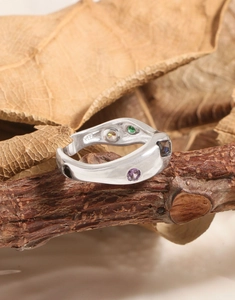 Macro detail of S925 silver ring with colorful zircons on a rustic wood branch