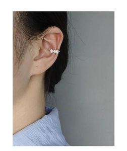 Detail of S925 silver bow ear cuff with sparkling white zircons on female model ear