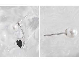 Vue macro d'une boucle d'oreille en argent S925 avec perle blanche et cœur noir