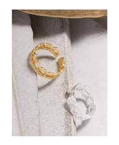 Detailed close-up of gold and silver hollow woven lace rings on stone texture