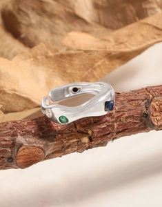 Detail of irregular S925 silver ring with multi-colored zircons on a wooden branch