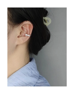 Close-up of a silver bow ear cuff with micro-pave cubic zirconia on a model's ear