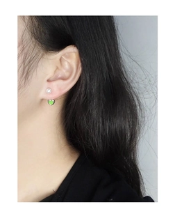 Détail de boucle d'oreille perle en argent s925 avec pendentif cœur vert derrière l'oreille