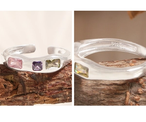 Macro detail of S925 sterling silver stamp and wave ring set with colorful zircons