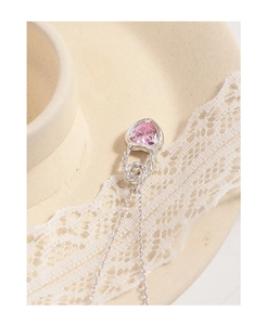 Close-up of pink heart zircon pendant with twisted silver bail on lace background