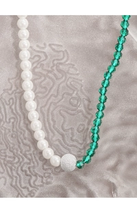 Detail of asymmetrical necklace with white pearls, green crystal beads and silver bead