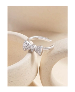 Macro detail of silver bow ear cuff with pavé zircons hanging on a ceramic cup edge