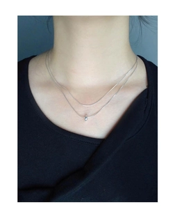 Detail of minimalist double-layered silver necklace with round pendant on model