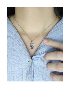 Close-up of S925 silver heart necklace with blue zircon on a woman's neckline
