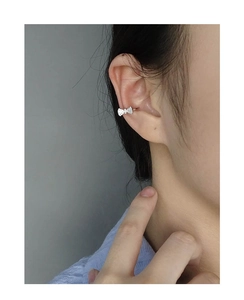 Detailed view of a silver bow-shaped ear cuff with pavé-set sparkling cubic zirconia