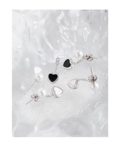 Vue détaillée des boucles d'oreilles cœur en argent avec émail noir et blanc et perles