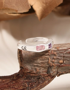 Macro detail of S925 silver adjustable ring with three colored gemstones on wood