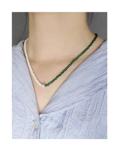 Detailed view of asymmetric necklace featuring white pearls and green faceted beads