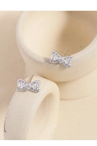 Macro shot of silver bow knot earrings with pavé zircon stones on a ceramic surface