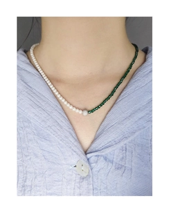 Detail of S925 silver necklace with white pearls and green faceted beads on neck