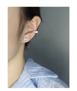 Close-up of S925 silver bow earrings and ear cuff with sparkling zircon on a model