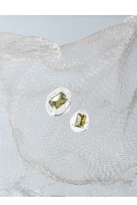 Macro shot of silver textured stud earrings with emerald-cut olive green zircon stones