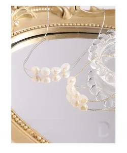 Detailed close-up of natural baroque pearls on a fine S925 silver chain over mirror