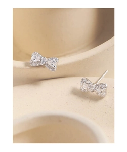 Macro shot of silver bow stud earrings with sparkling cubic zirconia on light background