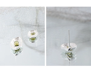 Macro shot of 925 silver stud earrings with green zircon and crinkled texture details