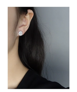 Close-up of silver irregular lava texture earrings with cubic zirconia on female ear