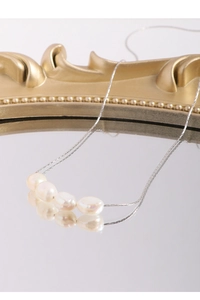 Detail of S925 silver necklace with four baroque pearls on a mirror reflection