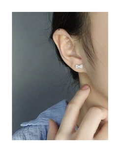 Close-up of a silver bow earring with zircon stones worn on the ear for a refined look
