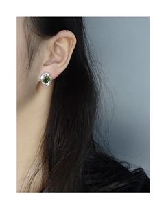 Macro shot of silver textured earring featuring a square emerald zircon on the ear