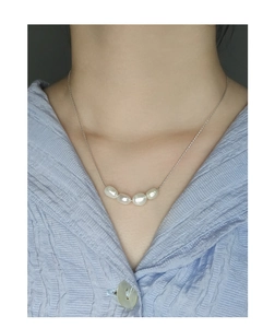 Detail of four natural baroque pearls on a fine S925 silver chain worn by a model