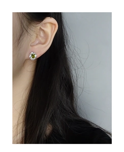 Close-up of olive green rectangular zircon earrings with silver textured finish