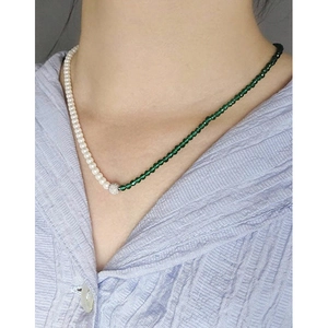 Elegant S925 silver necklace with green stones and pearls on a striped shirt