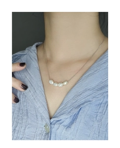 Close-up of five white baroque pearls on a slim silver S925 chain worn by a model