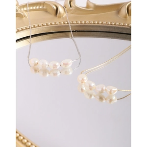 Minimalist Baroque pearl necklaces in gold and silver finish on a vintage mirror