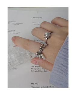 Detailed view of silver rings featuring white pearls and metallic spheres on a hand