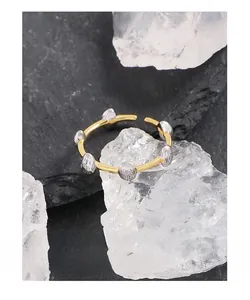 Macro view of gold open ring with silver textured drop charms on crystal base