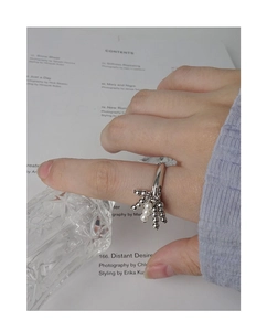 Detailed view of silver S925 beaded ring with pearl on finger against magazine