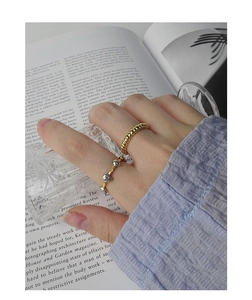 Close-up of gold twist ring and silver bean open ring worn for an elegant aesthetic