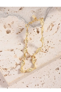 Detailed close-up of golden Mobius twist bracelet with adjustable chain on travertine
