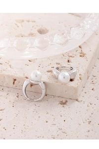 Close-up of minimalist S925 silver pearl hoop earrings on a natural stone base