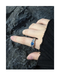 Macro detail of S925 silver ring with blue zircon and rugged volcanic rock texture